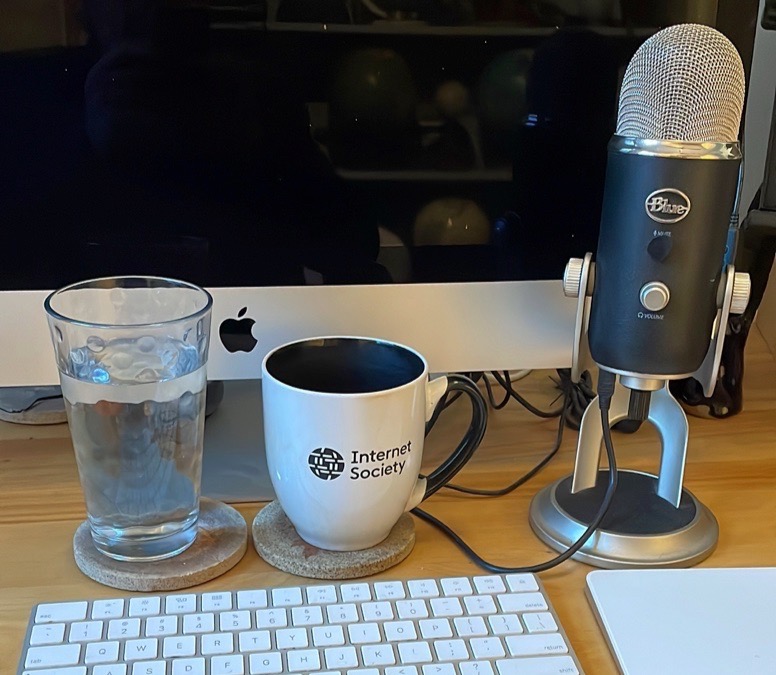 a glass, mug, and microphone in front of a computer